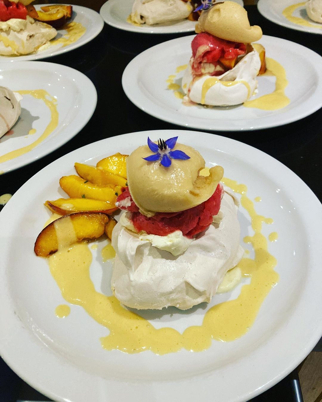 Pavlova with peach and berry ice cream, finished with a borage flower