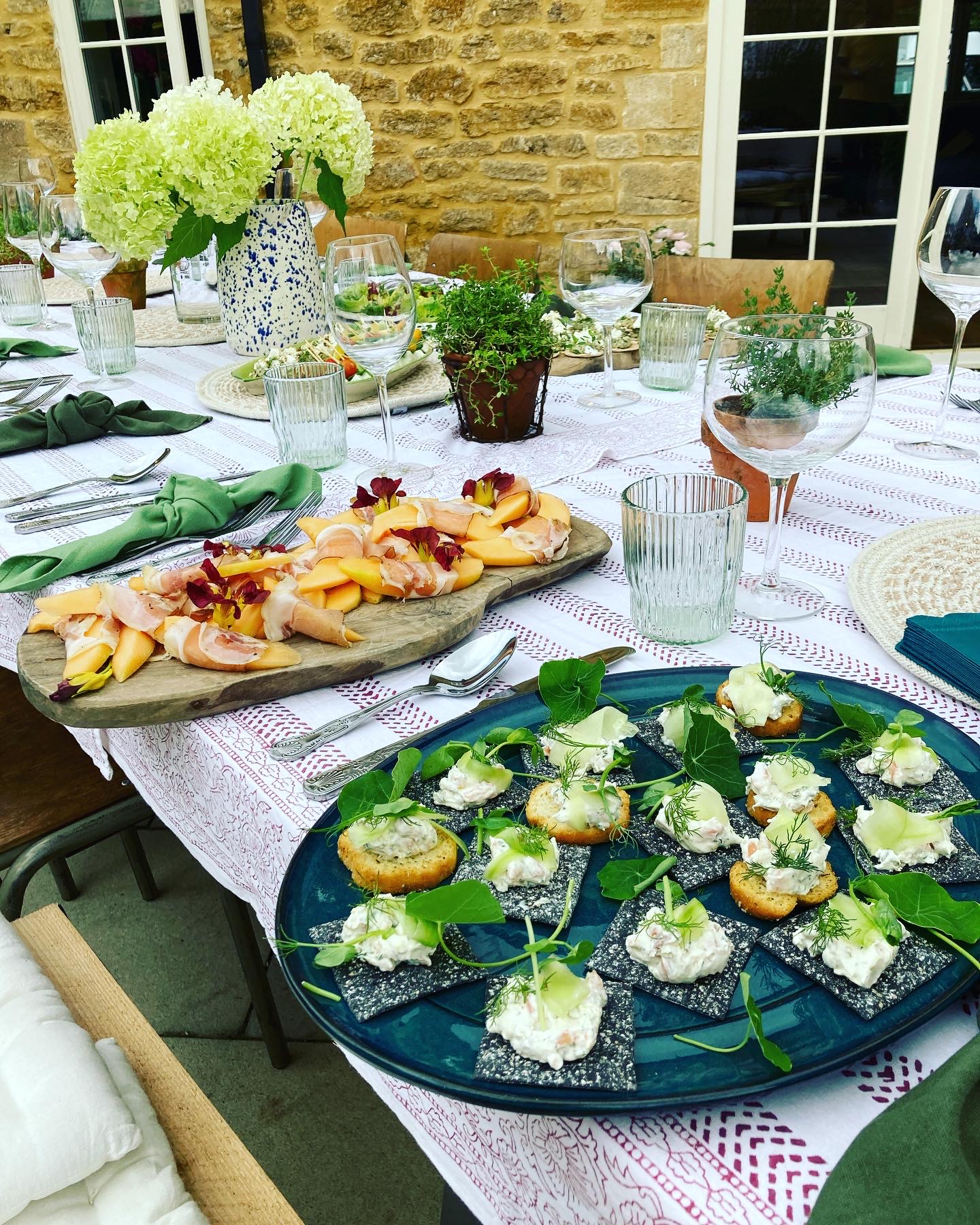 Outdoor summer table with prosciutto and melon board and seafood canapés